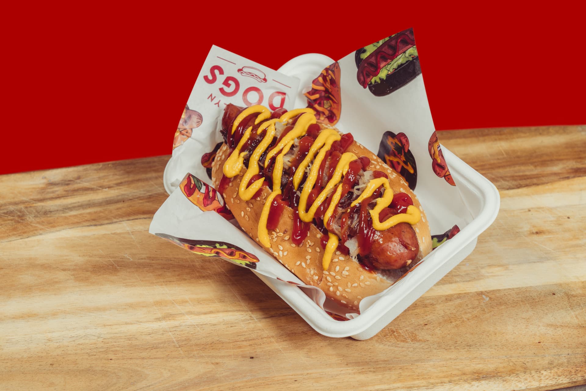 Brooklyn Dogs hot dog loaded with mustard and ketchup on branded paper